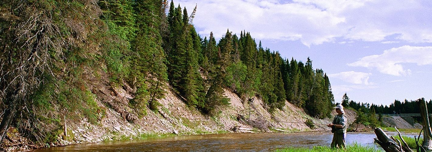 Rocky river with fisherman on the shoreline.