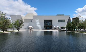 Un bâtiment de musée blanc, avec un grand bassin d'eau devant.