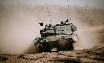 Un char d'assaut en vert se déplaçant sur de la terre.