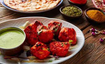 Red chicken pieces alongside a green dip