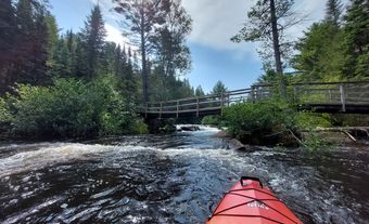 Devant d’un kayak face à un petit rapide et à un pont.