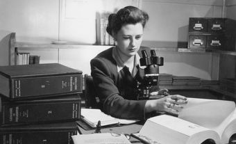 Diane Loranger travaille à un bureau avec des livres et un microscope.