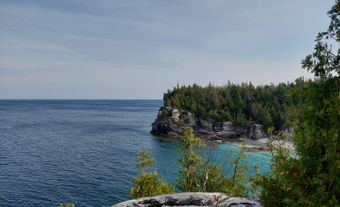 Falaise rocheuse au bord d’une eau d’un bleu éclatant.