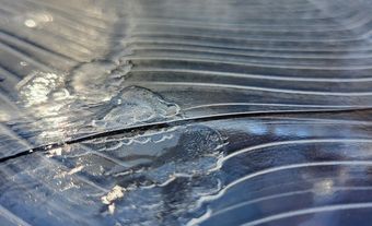 Fines crêtes sur la glace recouvrant une flaque d'eau.