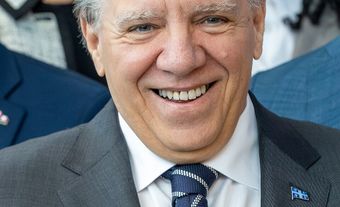 A white man in a suit smiling.
