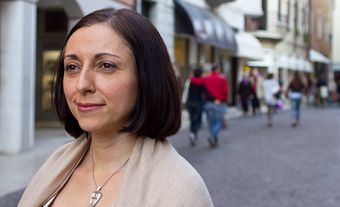 Une femme regardant sur le côté dans une rue, avec des passants flous en arrière-plan.