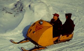 Photo of two poeple riding a Ski-Doo over snow