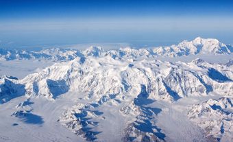 Areal shot of giant, snow-covered mountains.